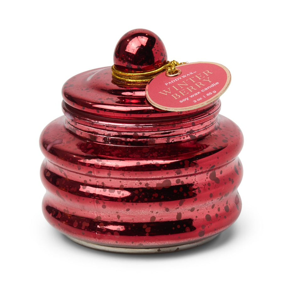 Red speckled candle with a decorative tag on a white background