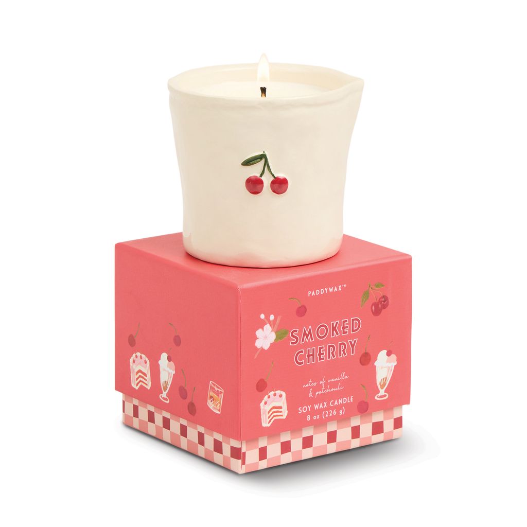 Candle with cherry design on a pink box labeled 'Smoked Cherry' on a white background