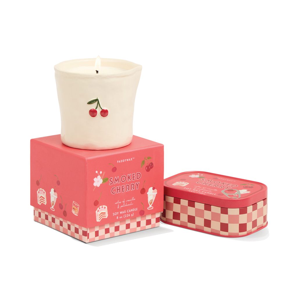 Candle with cherry design in a pink box and checkered tin on a white background