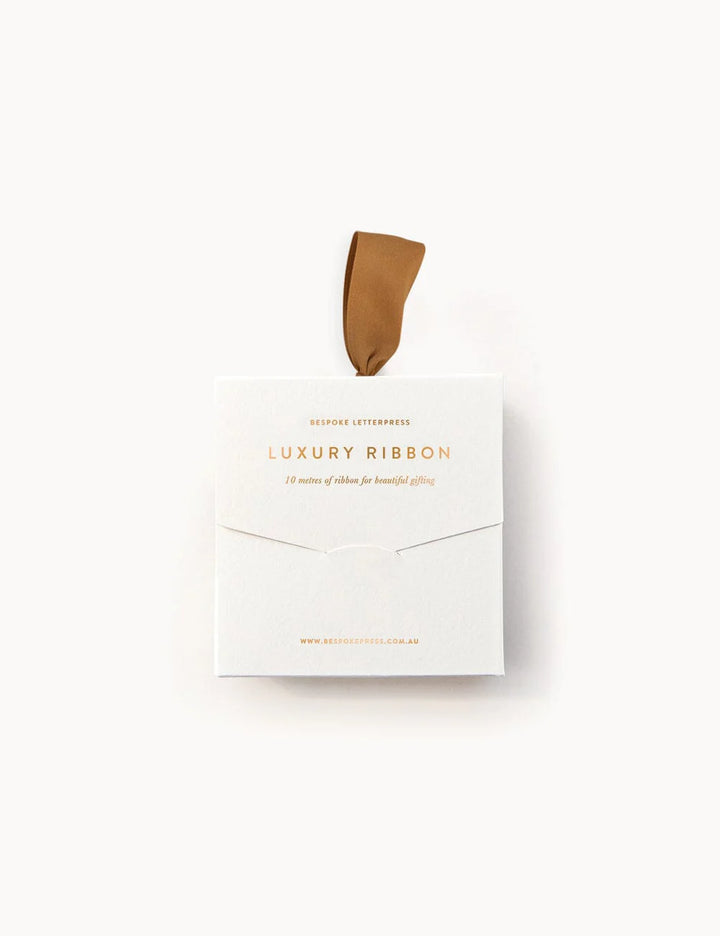 Box of luxury ribbon with a single ribbon strand on a white background
