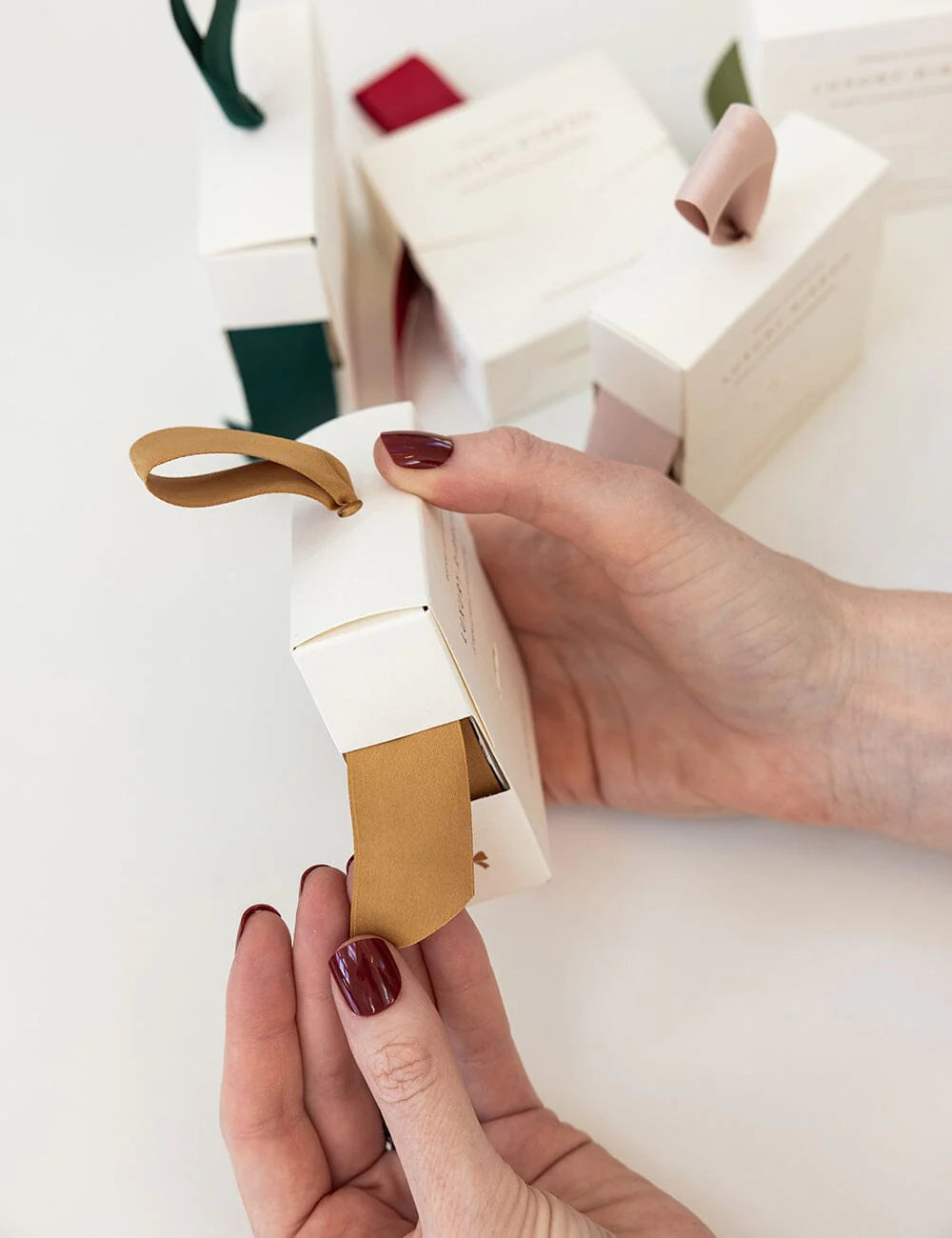 Hand holding different coloured ribbon in white packaging on a blurred background