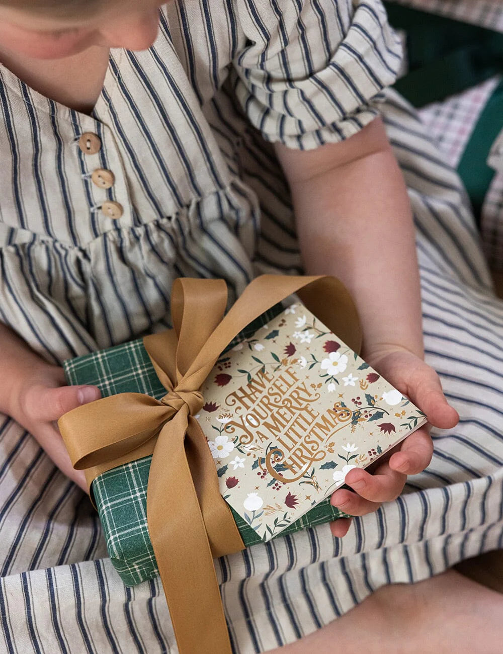 Child holding a small gift box with a decorative ribbon