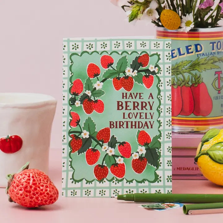 Greeting card with strawberry design and text 'Have a berry lovely birthday' on a pink background.