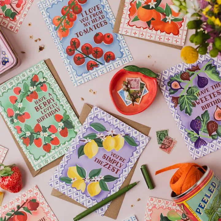 Collection of colorful greeting cards with fruit-themed designs on a table.