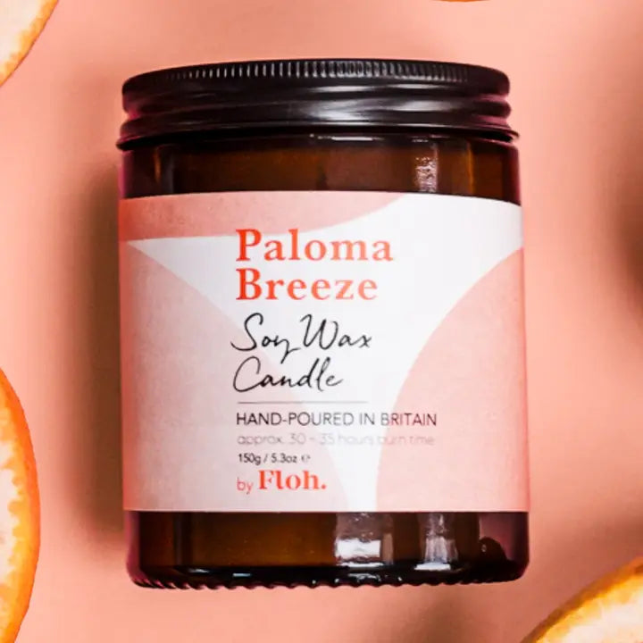 Paloma Breeze soy wax candle with a pink label on a peach background