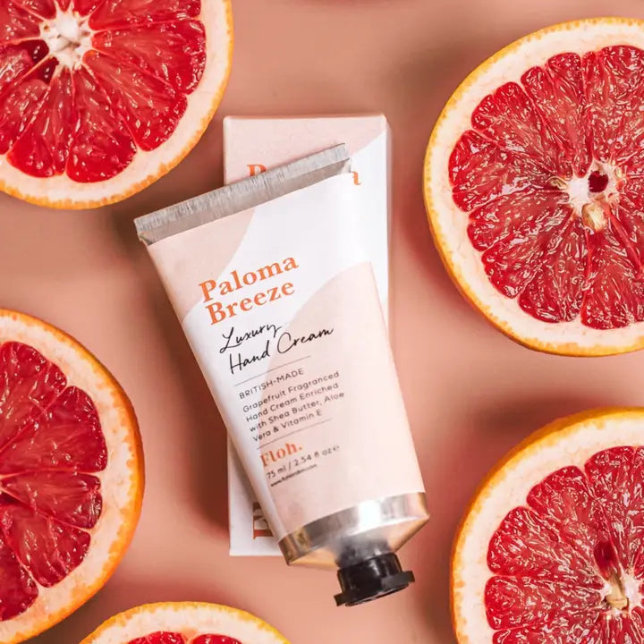 Paloma Breeze hand cream surrounded by sliced grapefruits on a matching background