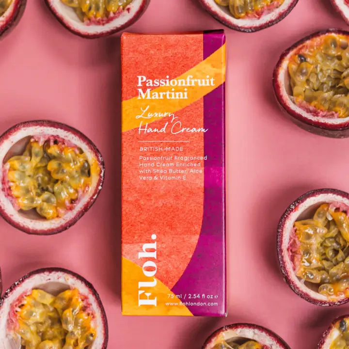 Passionfruit Martini hand cream box surrounded by passionfruit halves on a pink background