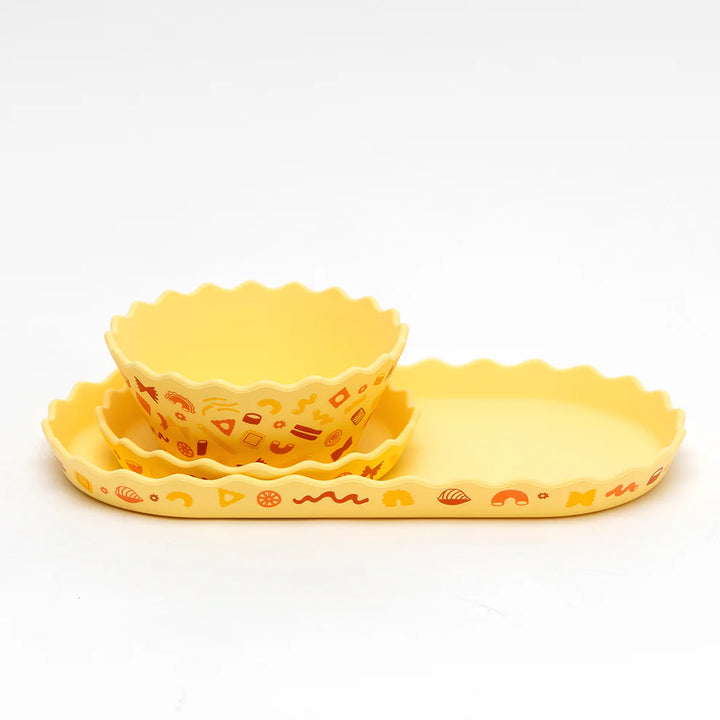 Set of three yellow silicone bowls with decorative patterns on a white background