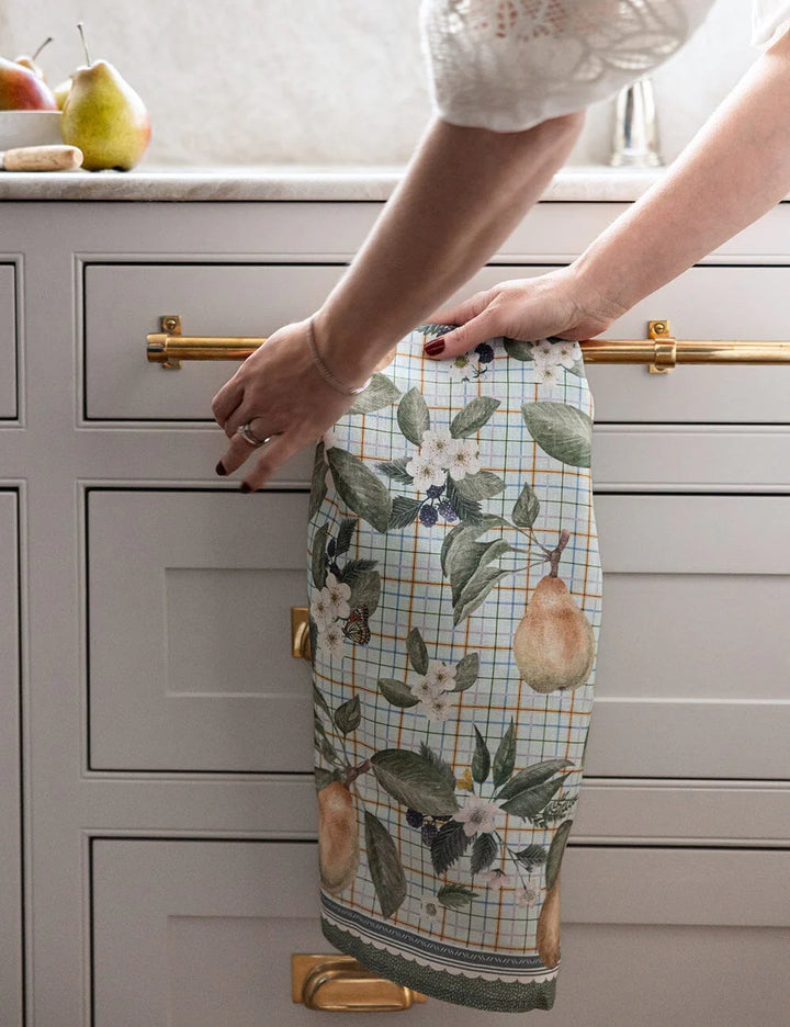 A floral and fruit linen tea towel hanging on a kitchen drawer