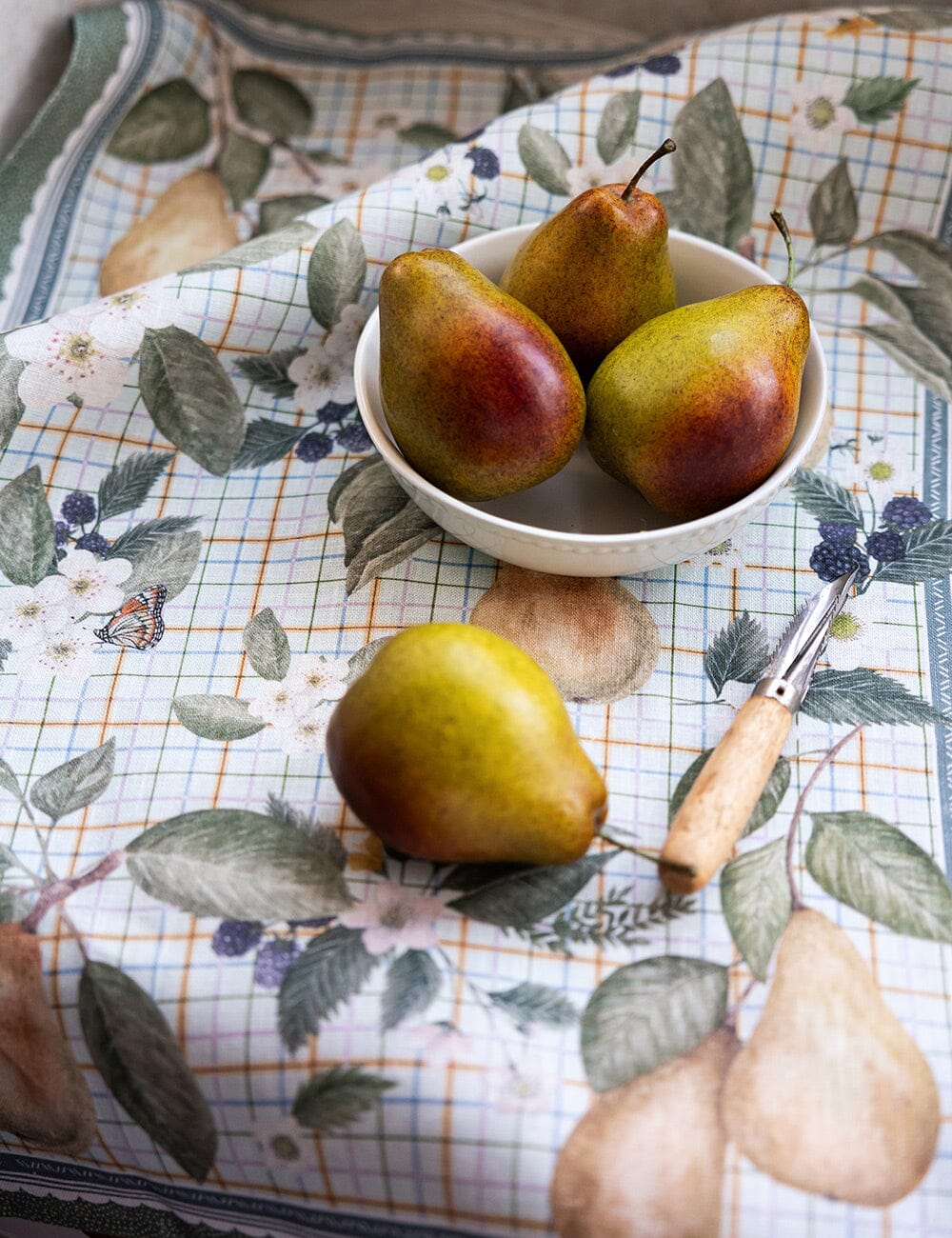 Pears in a bowl on a floral tablecloth