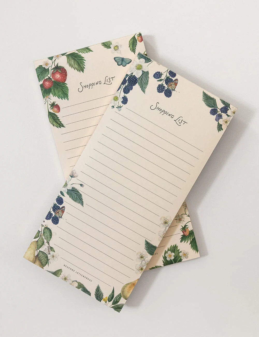 Two notepads with floral and fruit designs on a white background