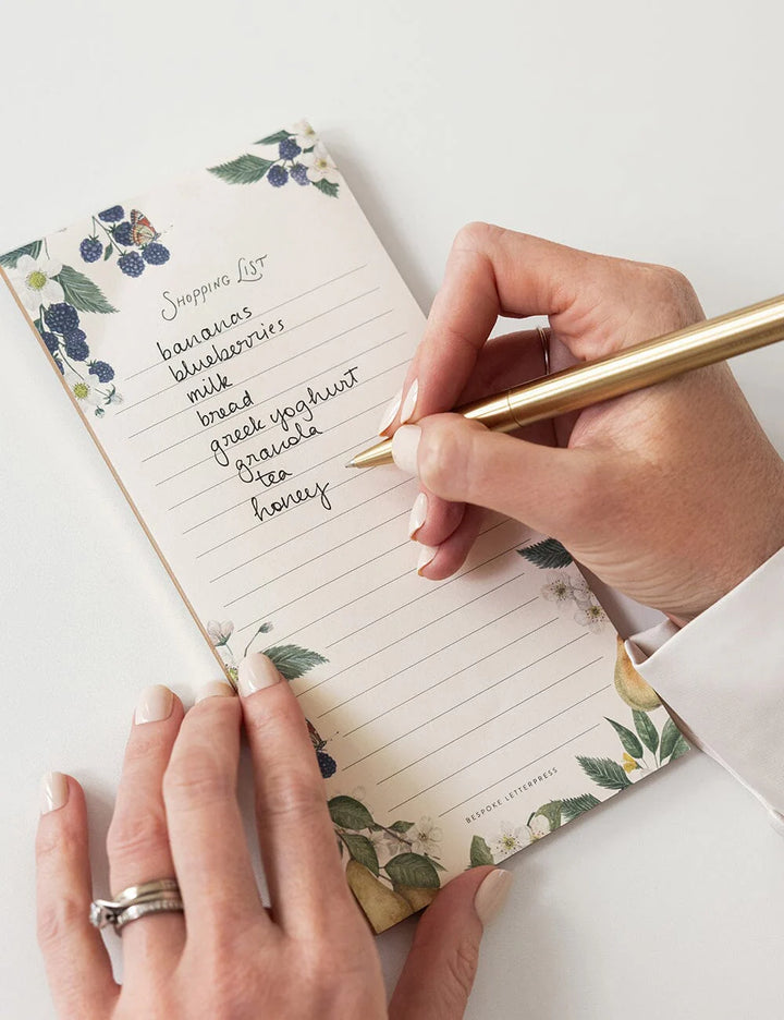 Person writing on a notepad with a gold pen