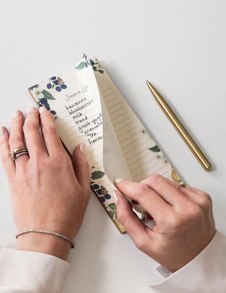 Person holding a floral notebook with a pen on a white background