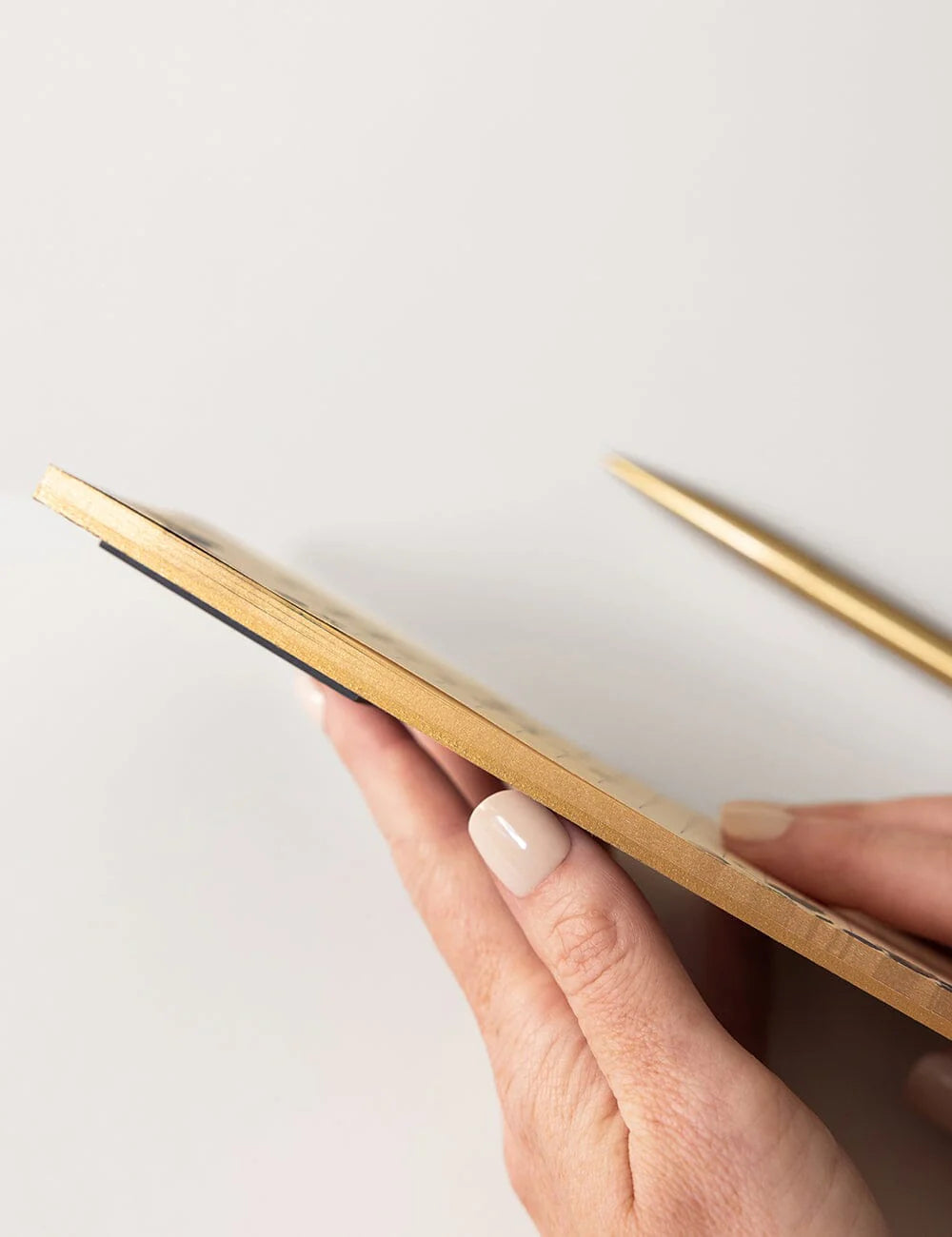 Hand holding a notepad with gold edges