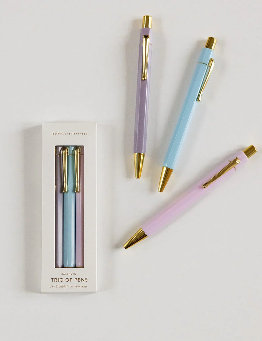 Three pastel-colored pens with gold accents on a white background, one pen outside its packaging.