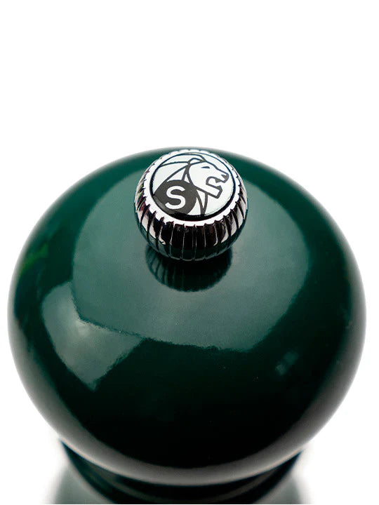 Green pepper grinder with a silver top on a white background