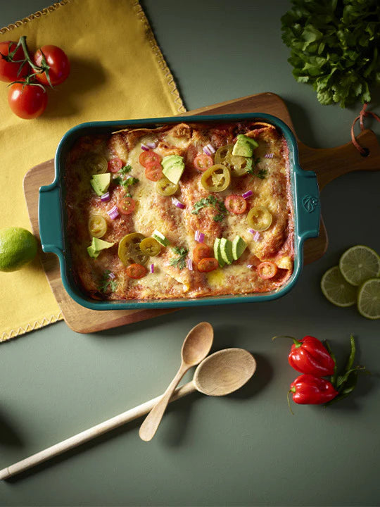 Baked dish in a green baking dish with vegetables on a green surface