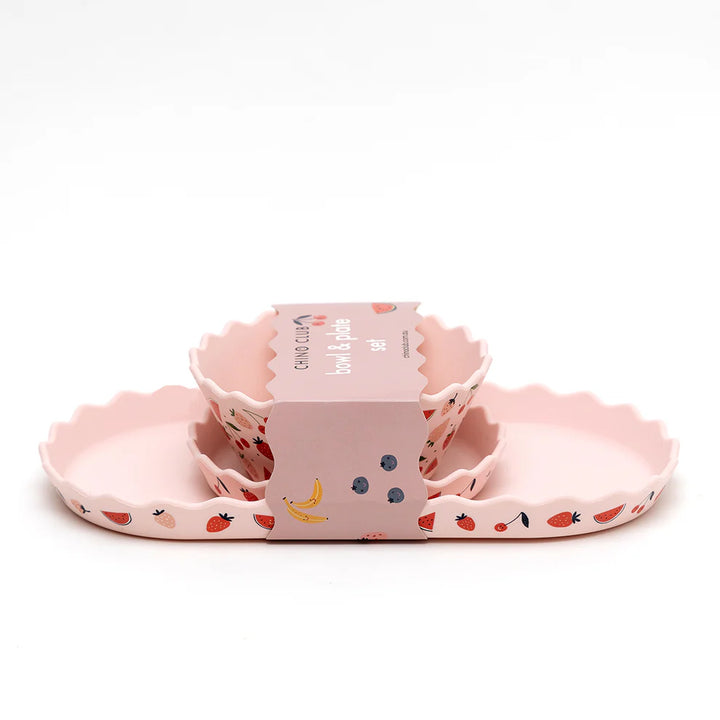 Set of pink silicone dishes with fruit patterns on a white background