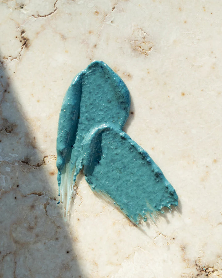 A swatch of a green face mask on a marble background