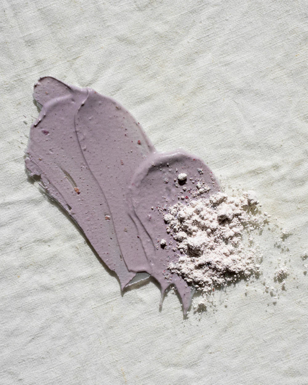 Purple face mask with a flaky residue on a textured white background