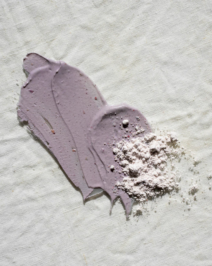 Purple face mask with a flaky residue on a textured white background