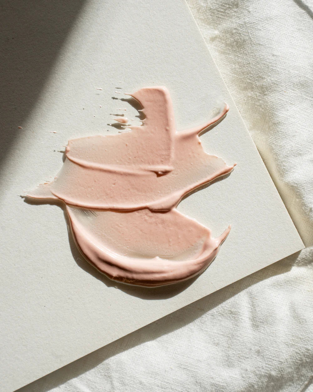Pink face mask product swatch on a light surface