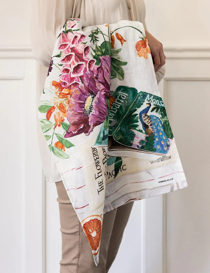 Person holding a floral-patterned towel with colorful designs against a neutral background