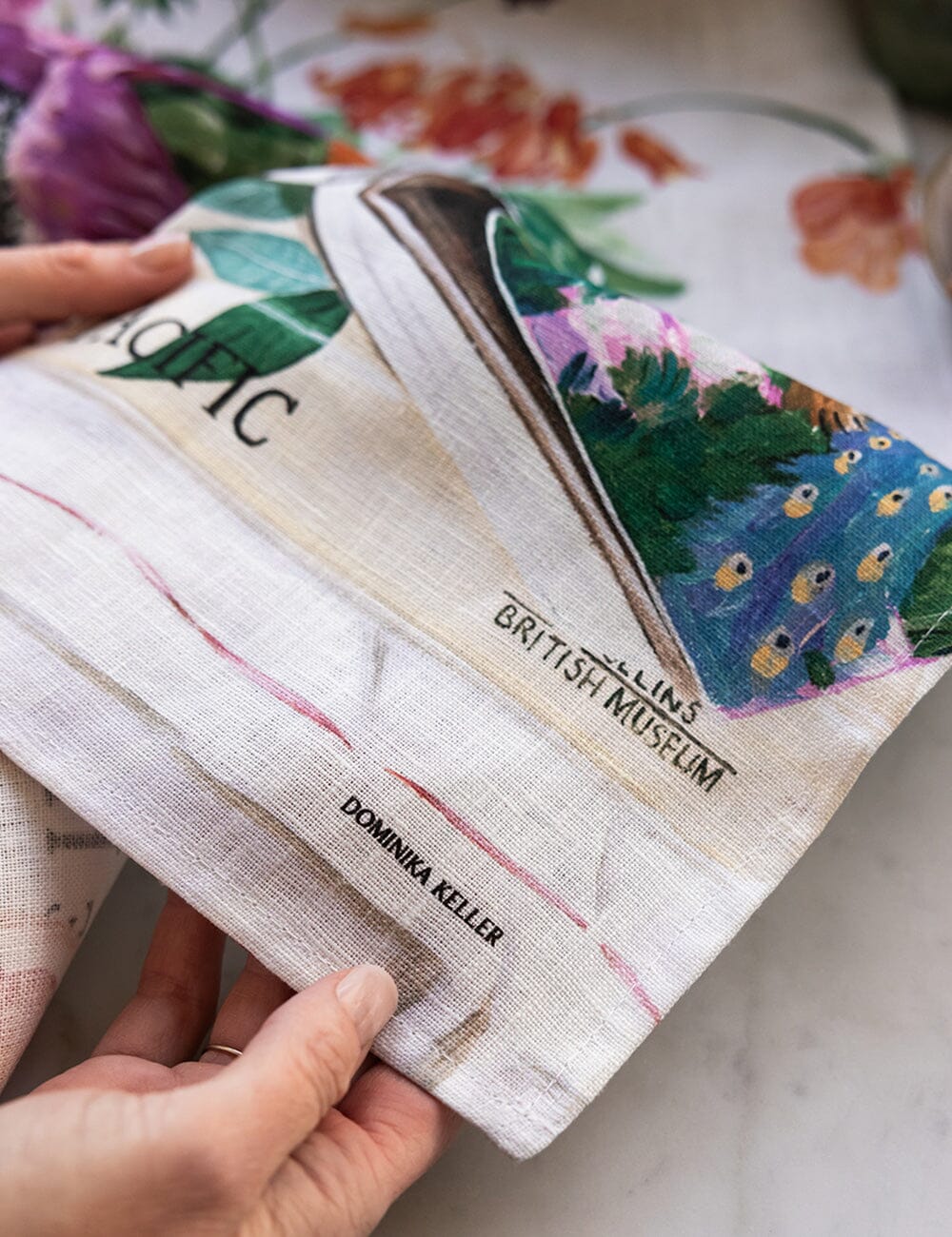 Hand holding a fabric item with 'British Museum' branding and artistic designs.