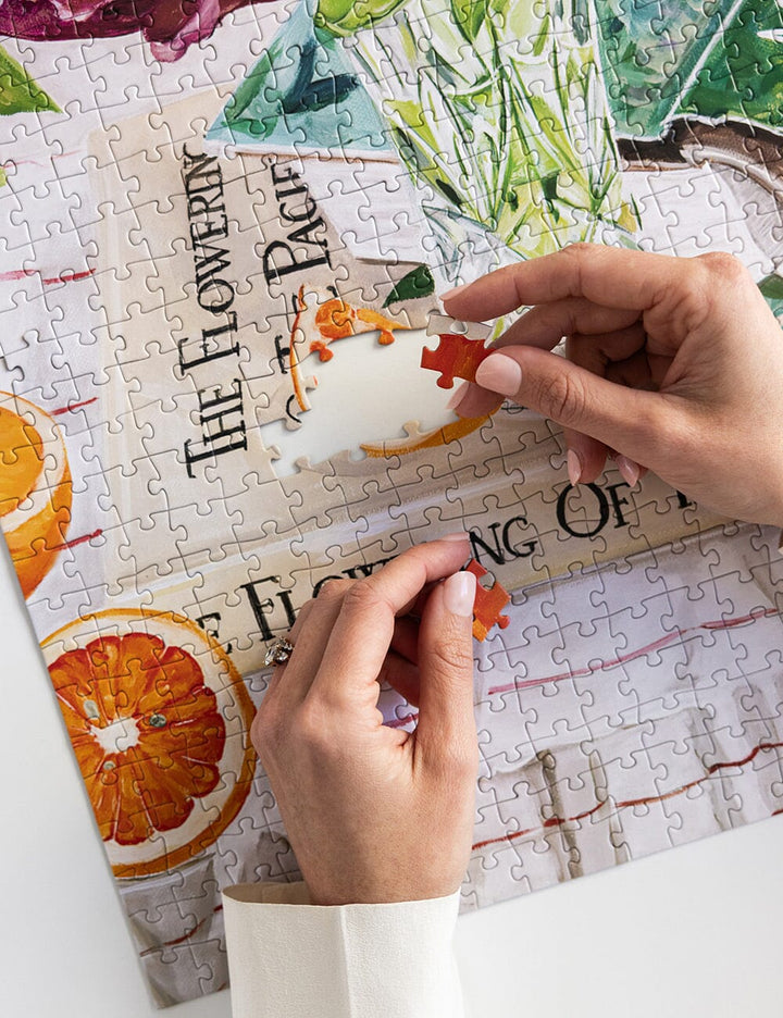 Person assembling a puzzle with colorful pieces on a partially completed puzzle.