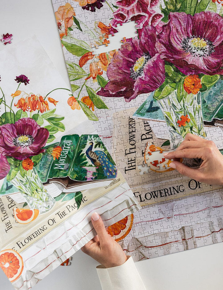 Floral-themed puzzle with a person assembling it on a white surface