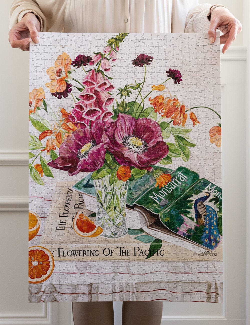 Person holding a completed puzzle with floral design and book pages.