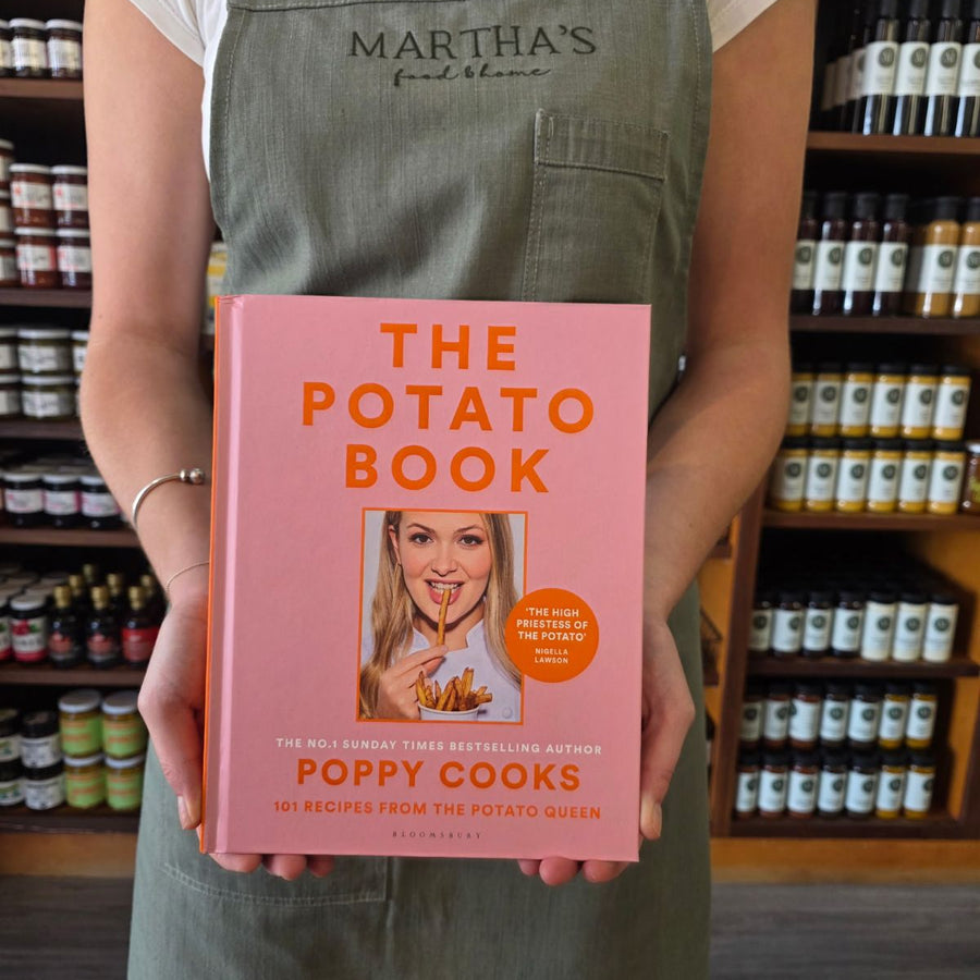 Person holding 'The Potato Book' by Poppy Cooks in a store setting