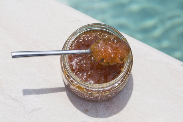 Jar of jam with a spoon on a ledge by a pool