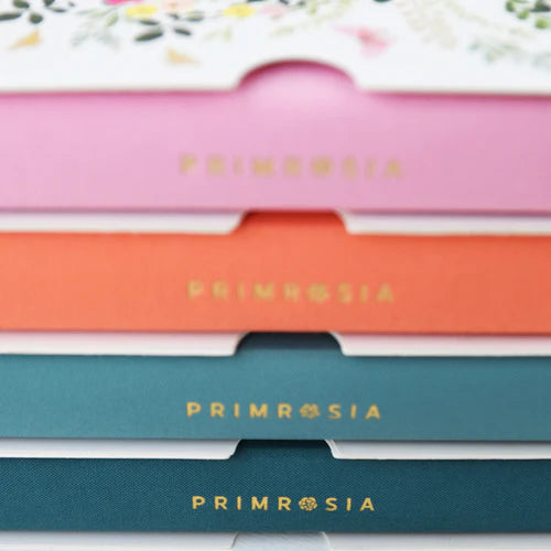 Stack of Primrosia notebooks in various colors with floral design on top.