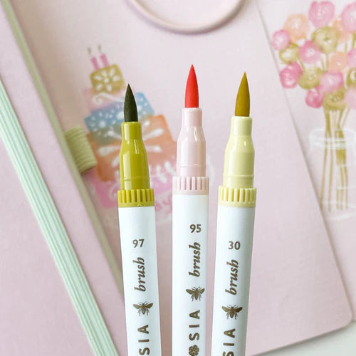 Three markers with different colored tips on a pink background