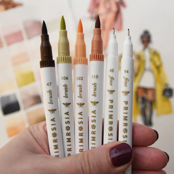 Set of Primrosia brush markers held by a hand with a blurred background