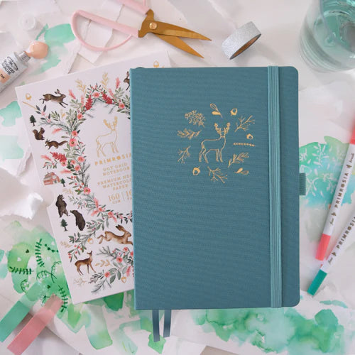 Teal notebook with deer design on a desk with stationery items