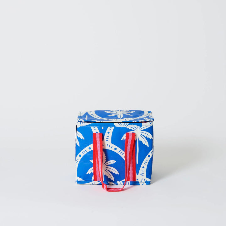 Blue insulated tote bag with palm tree pattern and red handles on a white background