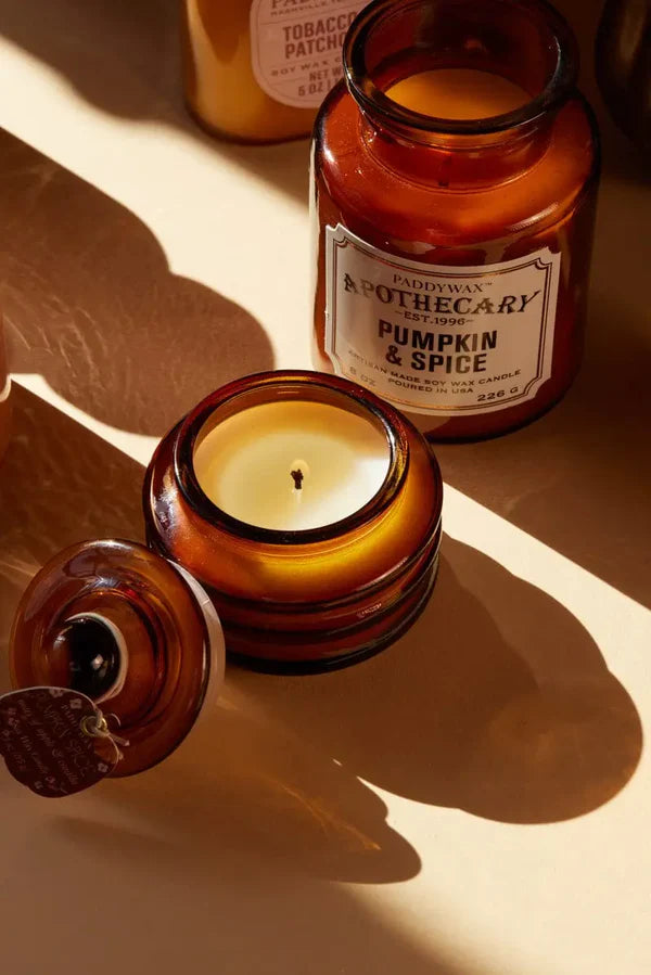 Two amber glass candles with labels on a light background