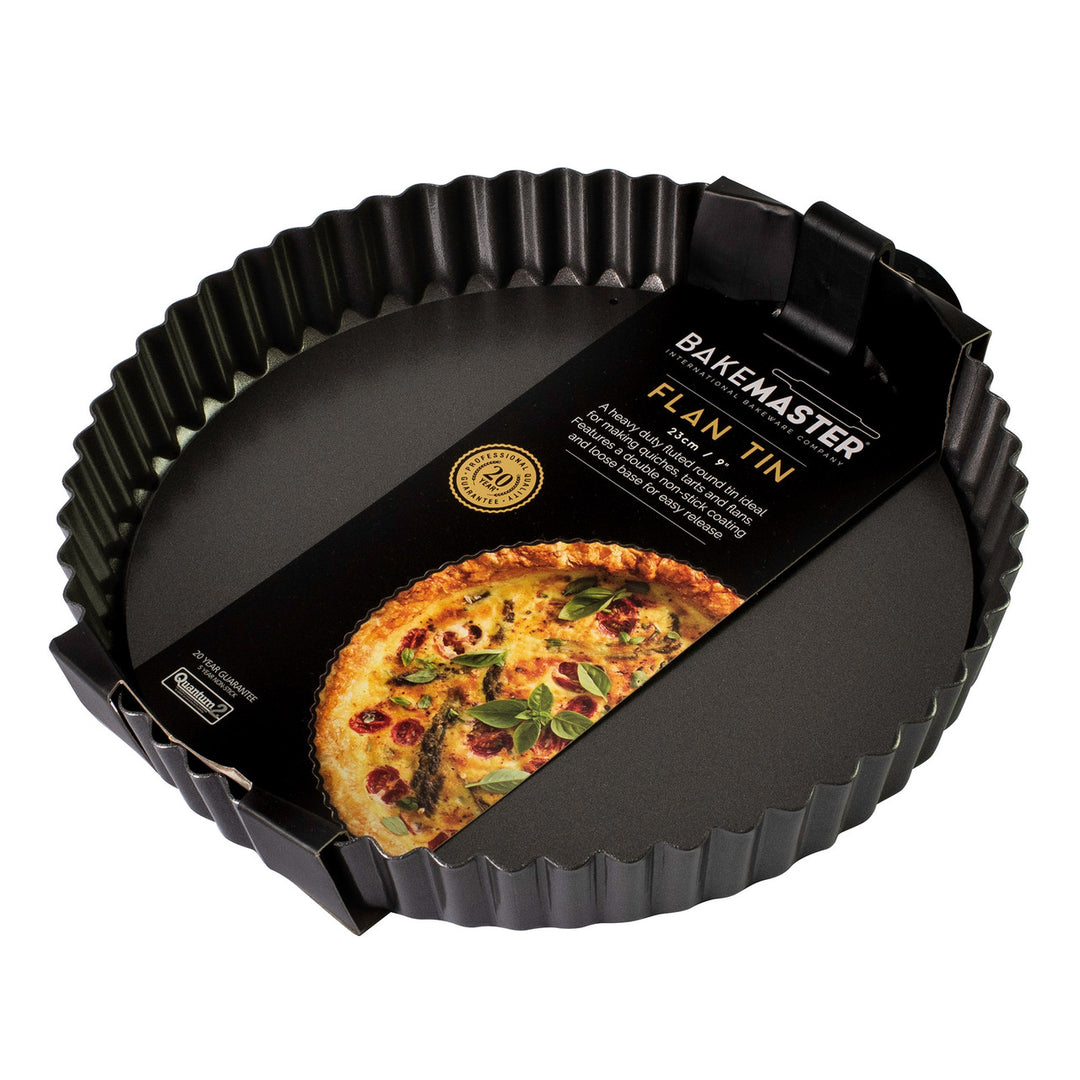 Black flan tin with a quiche on a white background