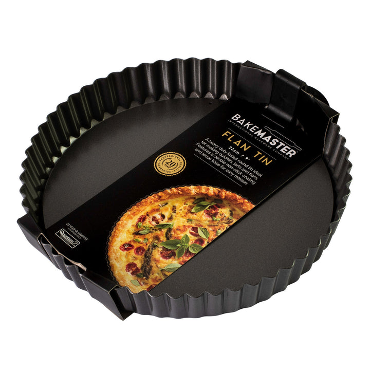 Black flan tin with a quiche on a white background