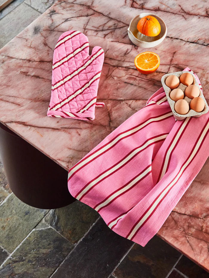 Marble table with a pink, white and r ed pott mitt & tea towel