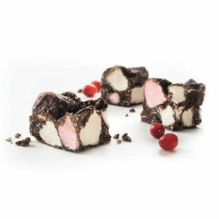 Chocolate and marshmallow candy pieces with red berries on a white background