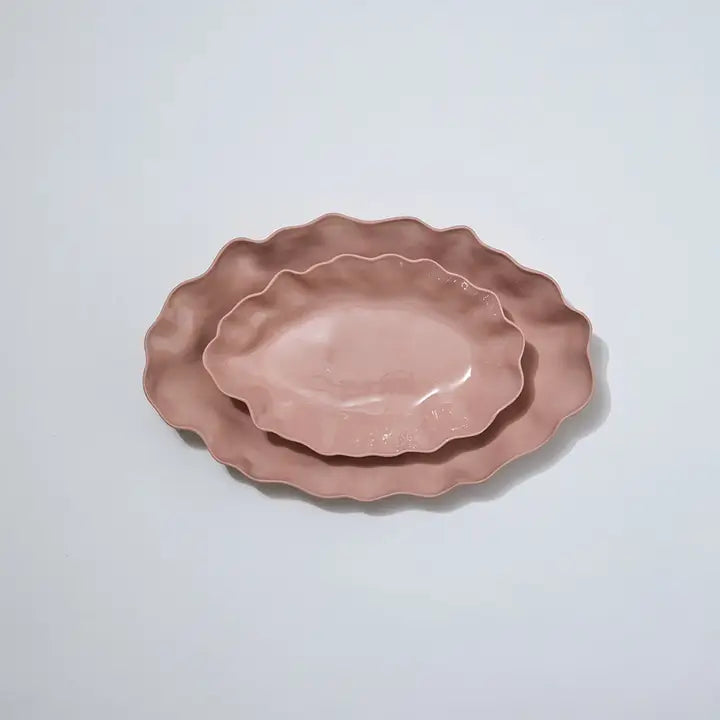 Two pink ceramic plates with scalloped edges on a light gray background