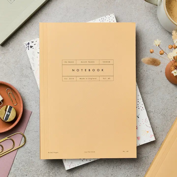 Yellow notebook on a gray surface with office supplies