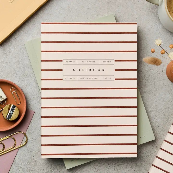 Striped notebook on a gray surface with office supplies
