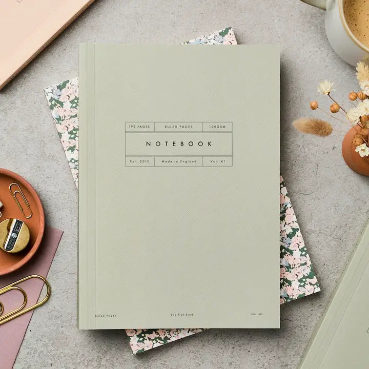 Light green Notebook on a gray surface with stationery items.