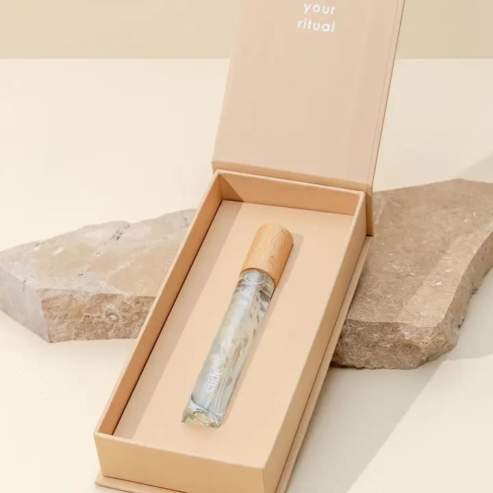 Parfum with cap in a beige box on a stone surface