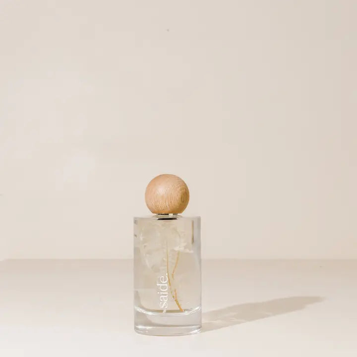 Clear glass interior fragrance bottle with wooden cap on a beige background