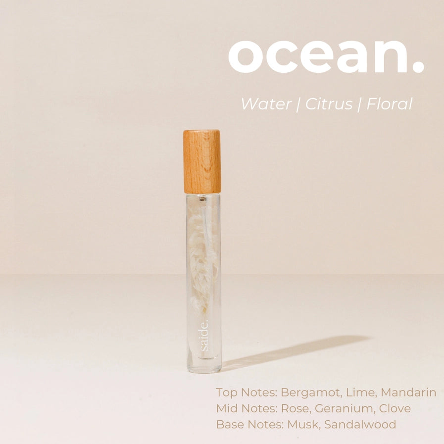 Vial of perfume with wooden cap on a beige background, labeled 'ocean'.